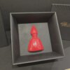 San Gennaro in ceramica rossa – Vista laterale Scultura di San Gennaro in ceramica rossa smaltata, raffigurazione stilizzata del patrono di Napoli, presentata in cornice nera moderna.