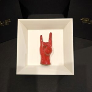 Scultura artigianale Corna Portafortuna in ceramica rossa, presentata in cornice bianca elegante, portafortuna tipico della tradizione napoletana.