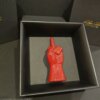 Il dito che dice tutto – scultura in ceramica rossa vista laterale in cornice nera Scultura pop in ceramica rossa a forma di mano con dito medio, un’opera ironica e provocatoria che non ha bisogno di parole.