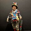 Dettaglio del busto dello Sciò Sciò Portafortuna con valigia e ombrello colorato, arricchito da simboli scaramantici.