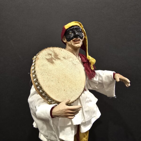 Pulcinella con tamburello e pantaloni gialli – vista laterale Vista laterale Pulcinella con tamburello e pantaloni gialli, scultura artigianale napoletana.