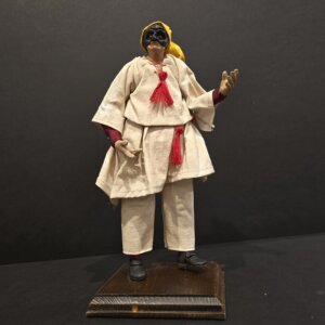Scultura in terracotta di Pulcinella con cappello giallo e nappine rosse, realizzata a mano.