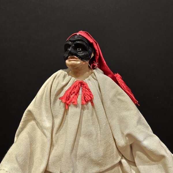 Pulcinella con berretto rosso – dettaglio ravvicinato Primo piano della scultura di Pulcinella con maschera nera e berretto rosso, realizzata a mano in terracotta.