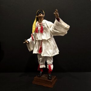 Pulcinella con berretto giallo e braccia alzate statua frontale Statua di Pulcinella con berretto giallo e braccia alzate in terracotta, vista frontale.
