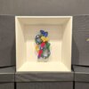 Scultura in ceramica colorata dell’Asso di Spade, decorata a mano con dettagli blu, verdi e dorati, esposta in cornice bianca elegante.