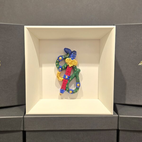 Scultura in ceramica colorata dell’Asso di Spade, decorata a mano con dettagli blu, verdi e dorati, esposta in cornice bianca elegante.