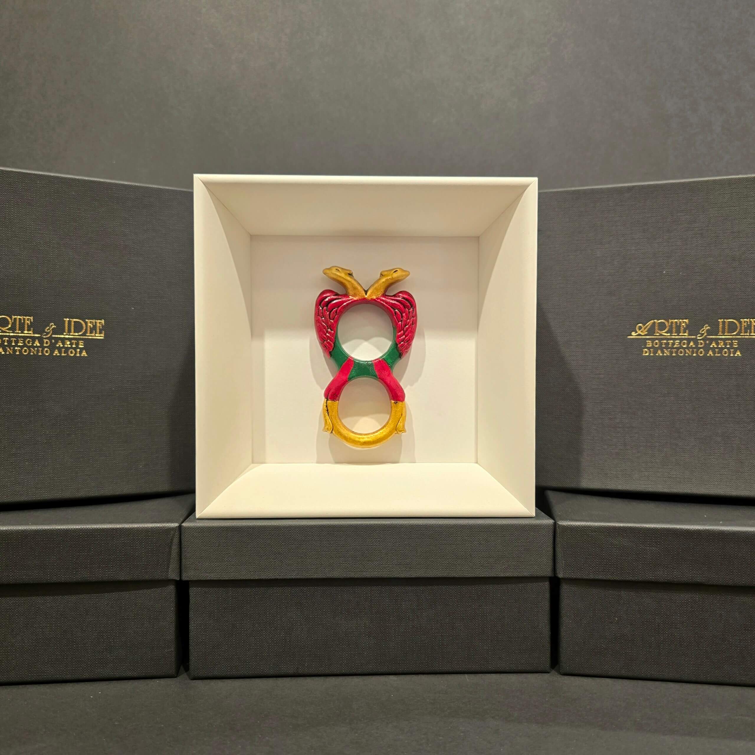 Scultura in ceramica colorata dell’Asso di Denari, realizzata e dipinta a mano, presentata in cornice bianca con sfondo elegante nero.