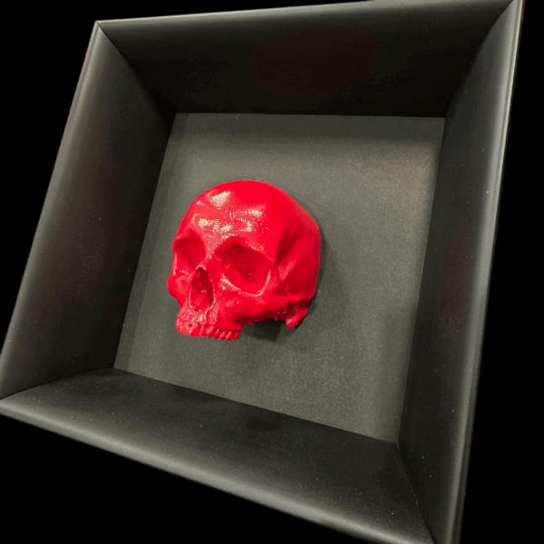 Dettaglio ravvicinato e angolato della scultura a forma di teschio umano con finitura oro, che evidenzia i riflessi e la tridimensionalità dell'opera.