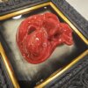 Dettaglio Scultura Ceramica Rossa e Cornice Oro Vista angolare ravvicinata che evidenzia il rilievo della maschera di Pulcinella smaltata di rosso e i dettagli della cornice interna dorata.