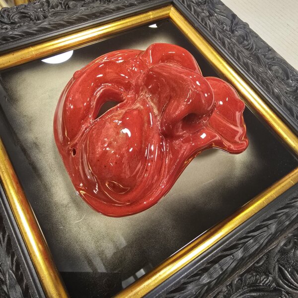 Dettaglio Scultura Ceramica Rossa e Cornice Oro Vista angolare ravvicinata che evidenzia il rilievo della maschera di Pulcinella smaltata di rosso e i dettagli della cornice interna dorata.