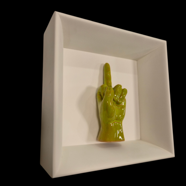 quadro-provocatorio-ceramica-verdino Prospettiva angolata sinistra del quadro artigianale con il gesto del dito medio, finitura pop verde chiaro.