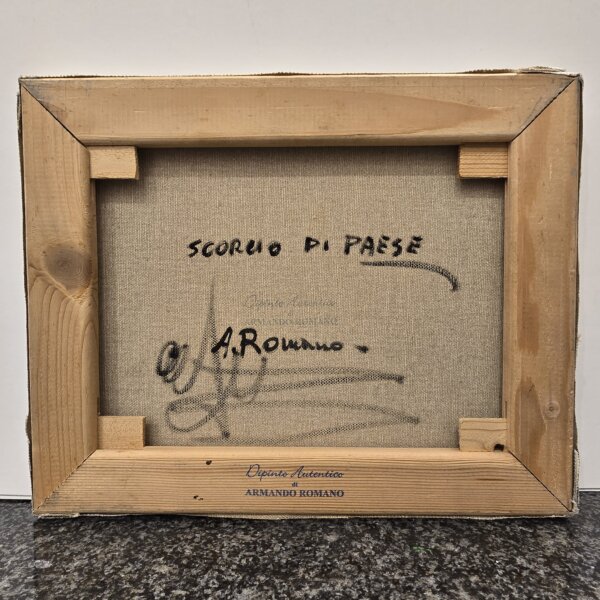 Retro tela Scorcio di paese con firma e timbro Armando Romano Retro del dipinto su telaio in legno che mostra la scritta "Scorcio di paese", la firma autografa "A. Romano" e il timbro blu "Dipinto Autentico di Armando Romano".