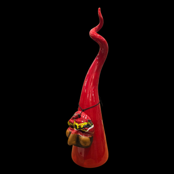 Vista di tre quarti del corno rosso in ceramica che mostra la curvatura sinuosa, la superficie smaltata brillante e il profilo della maschera.